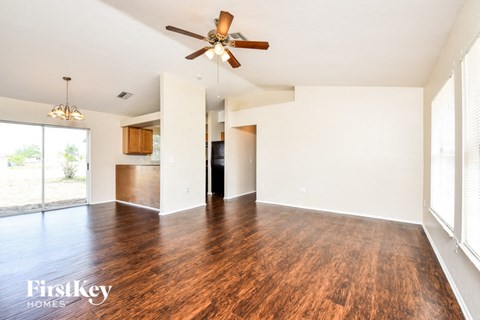 A spacious room with wooden floors and a ceiling fan.