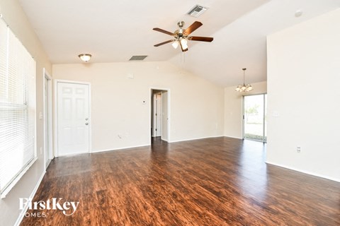 A spacious room with wooden floors and a ceiling fan.