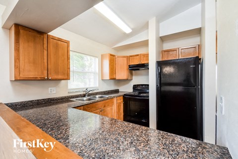 A kitchen with granite countertops and wooden cabinets.