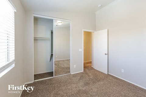 a bedroom with a closet and a window and a carpeted floor