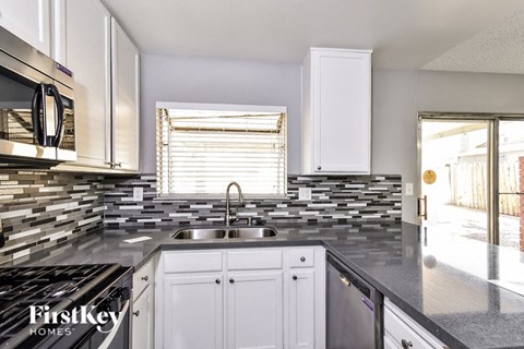 a kitchen with white cabinets and a sink and a window