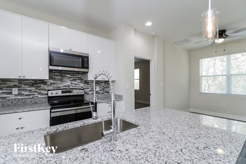 a kitchen with white cabinets and a sink and a stove