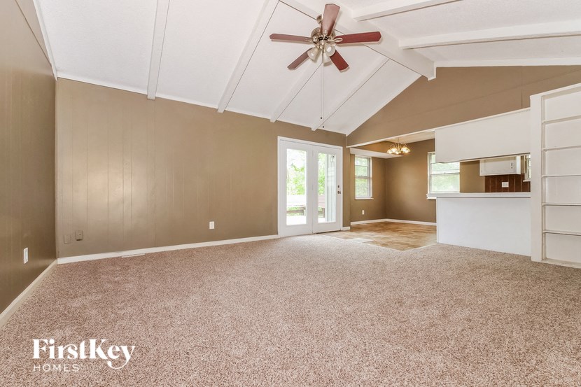 A spacious room with a ceiling fan and a carpeted floor.