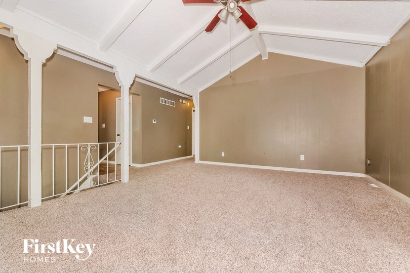 A spacious room with a fan and carpeted floor.