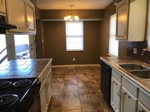A kitchen with brown walls and a black stove top oven.