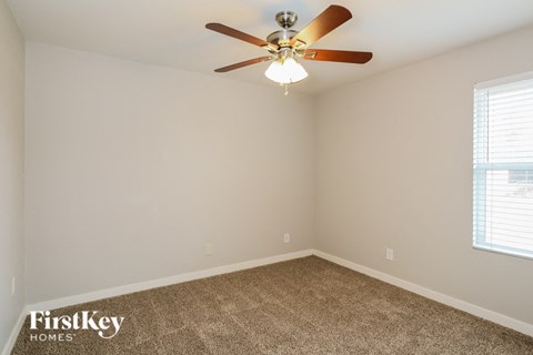 the bedroom has a ceiling fan and a carpet