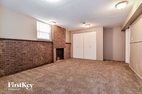 a living room with a brick fireplace and a carpeted floor