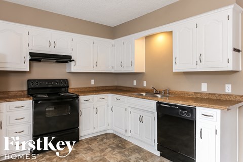 A kitchen with white cabinets and a black oven.
