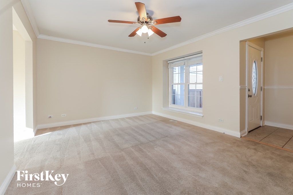 an empty living room with a ceiling fan and a window