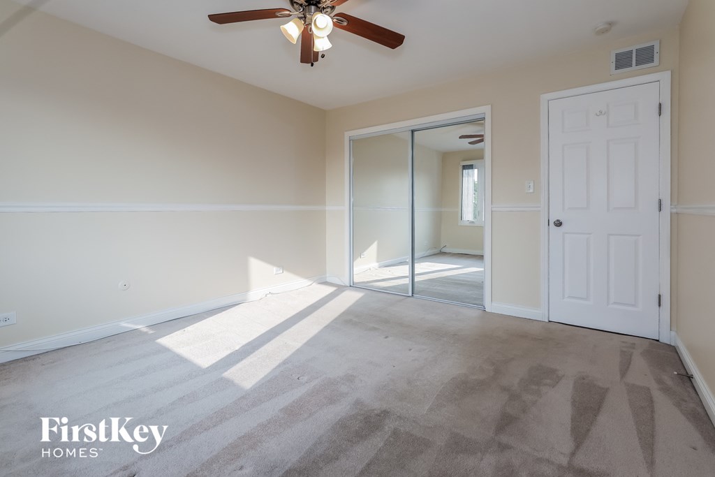 an empty living room with a ceiling fan and a white door