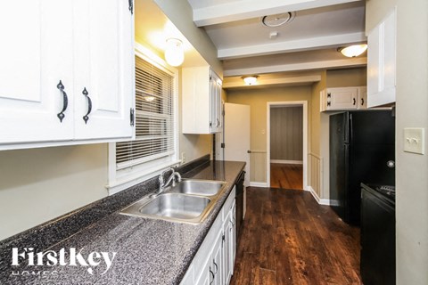 a kitchen with granite counter tops and white cabinets and a hallway with a black door