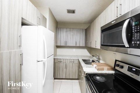 A kitchen with a white fridge and black microwave.