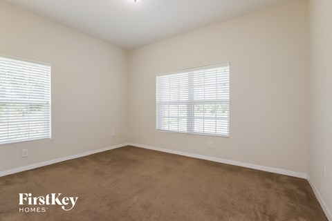 a bedroom with a carpeted floor and two windows