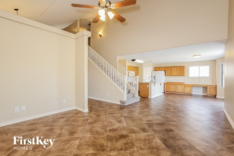 A spacious living room with a staircase and a ceiling fan.