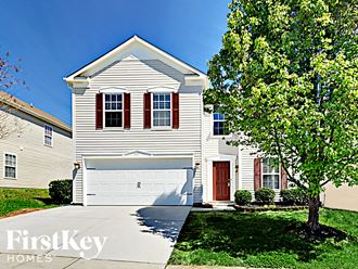 a white house with a white garage door and a tree