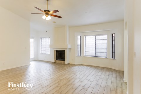 A spacious living room with a fireplace and a ceiling fan.
