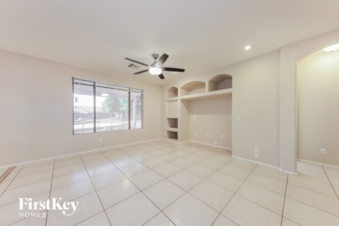 an empty living room with a ceiling fan and a window