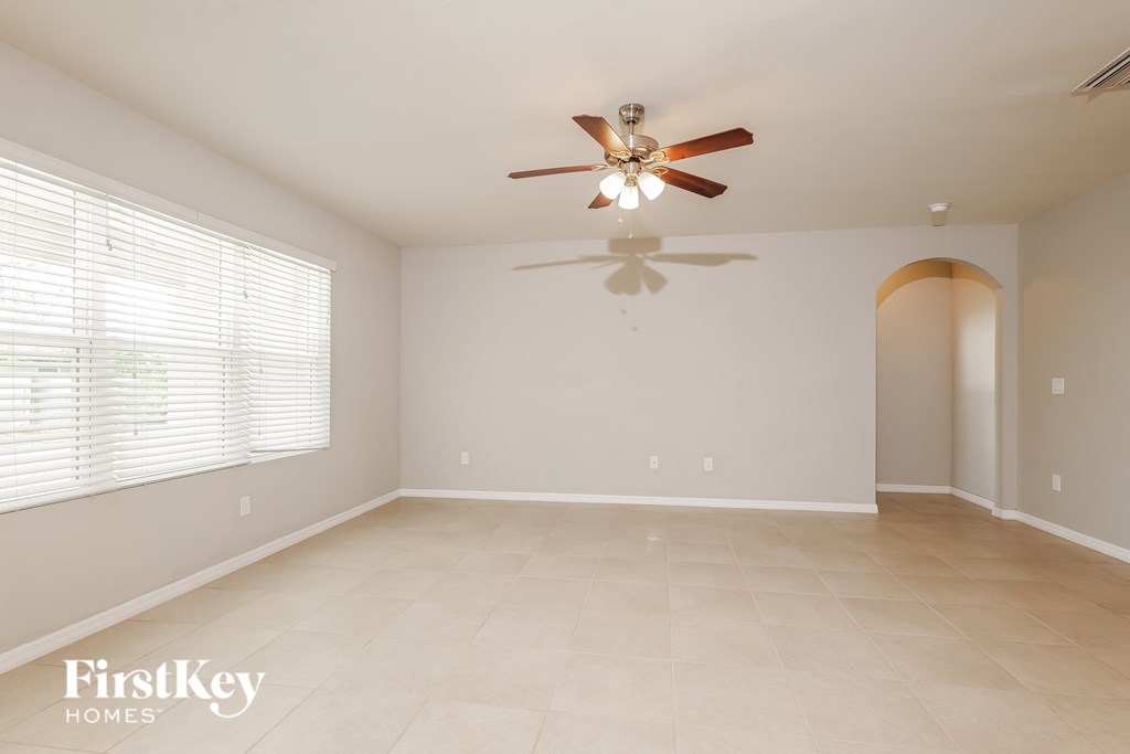 A spacious room with a ceiling fan and a doorway leading to another room.
