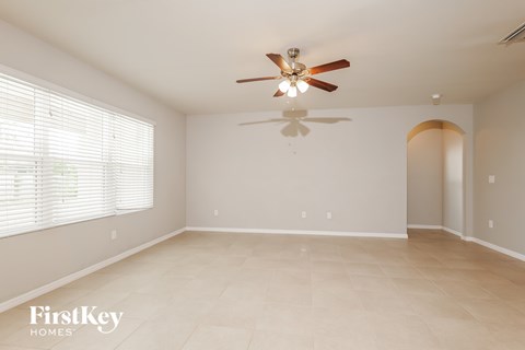 A spacious room with a ceiling fan and a doorway leading to another room.