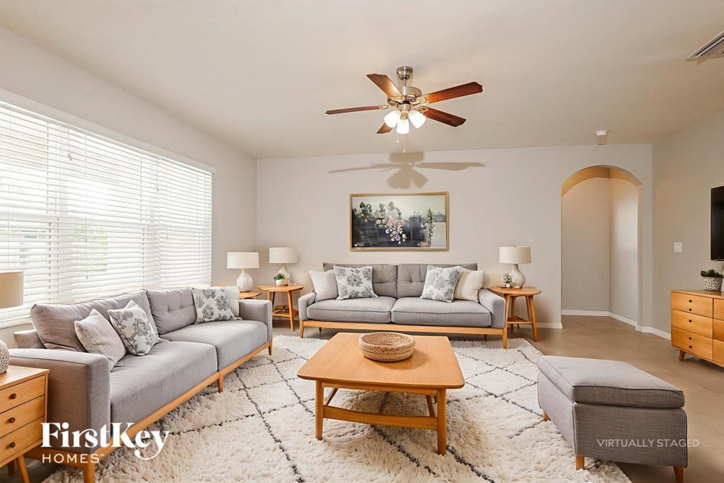 A living room with a grey couch, a wooden coffee table, and a painting on the wall.
