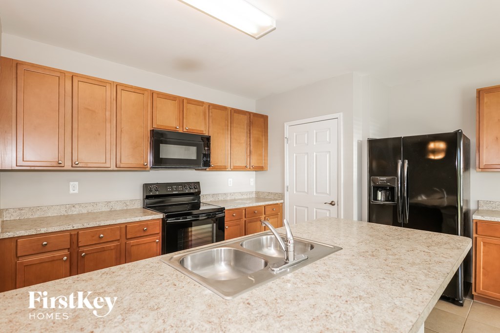 A kitchen with wooden cabinets and a black refrigerator.