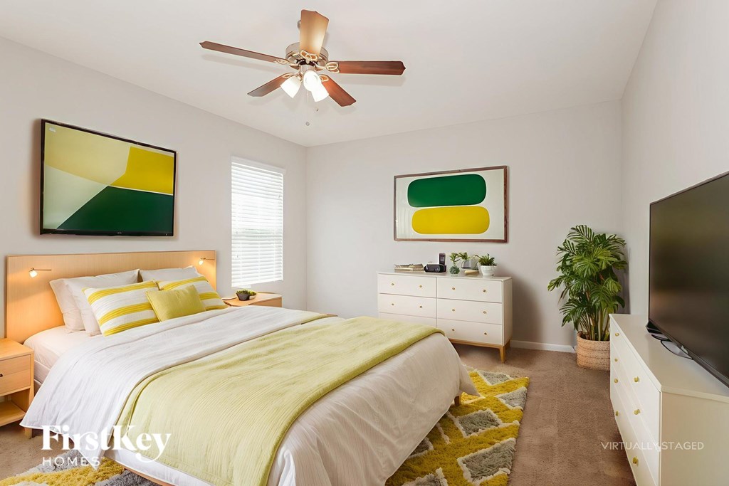 A bedroom with a bed, dresser, and ceiling fan.