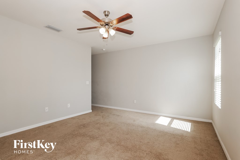 A room with a ceiling fan and carpeted floor.