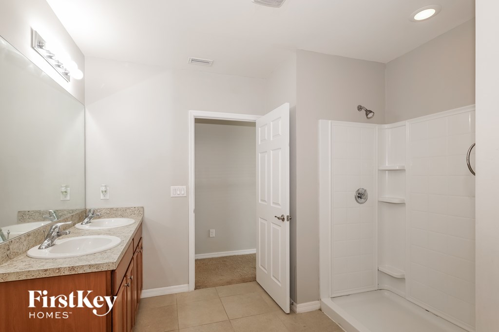 A bathroom with a sink, mirror, and shower.