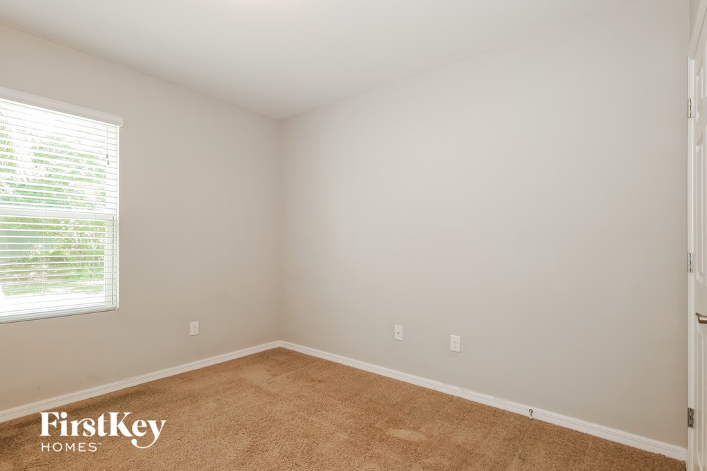 A room with a carpeted floor and a window with blinds.