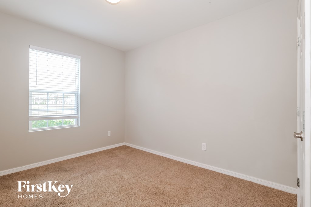 A room with a carpet floor and a window with blinds.