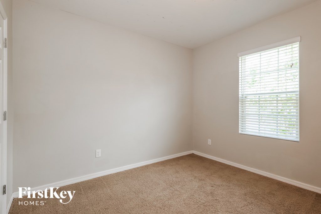 A room with a carpeted floor and a window with blinds.