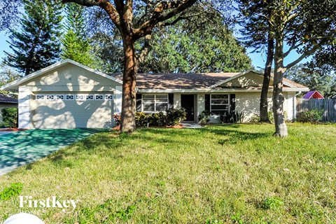 a house with a yard and trees in front of it