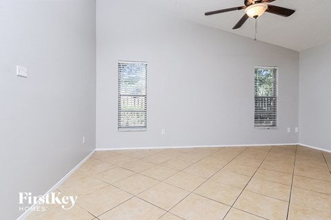 a empty living room with a ceiling fan and a tiled floor