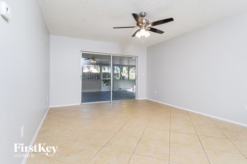 an empty living room with a ceiling fan and a tile floor