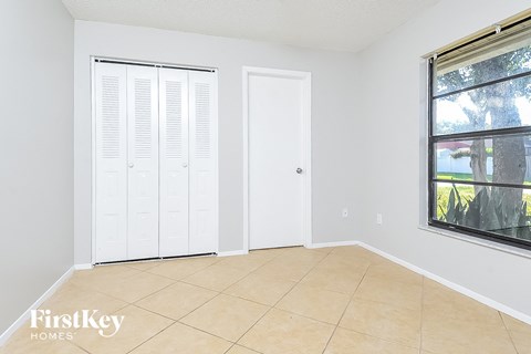 a bedroom with white shutters on the window and a tiled floor