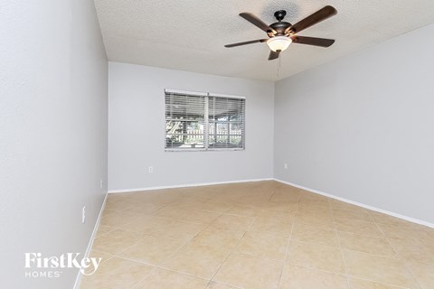 an empty living room with a ceiling fan and a window