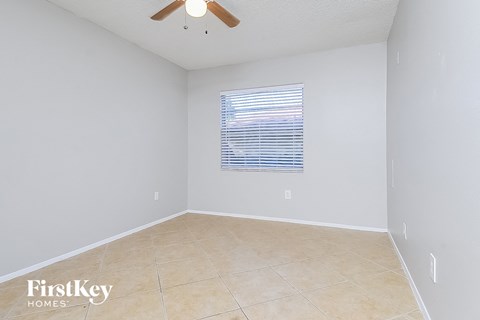 an empty room with a window and a ceiling fan