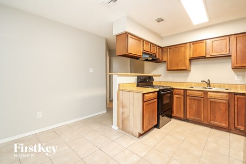 A kitchen with wooden cabinets and a tiled floor.