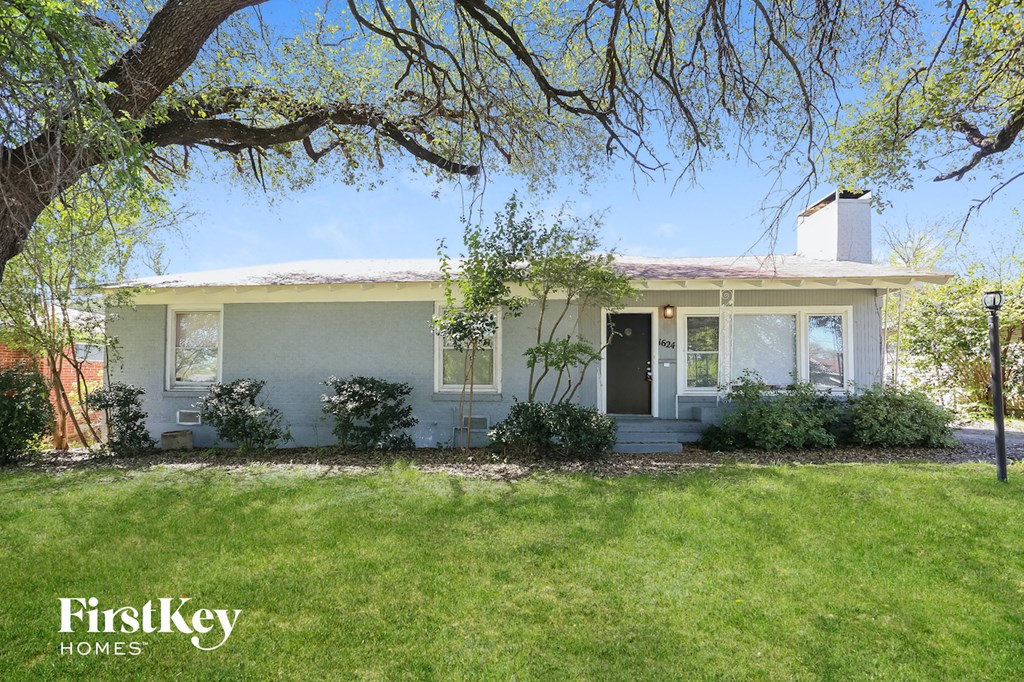 a white house with a lawn and a tree