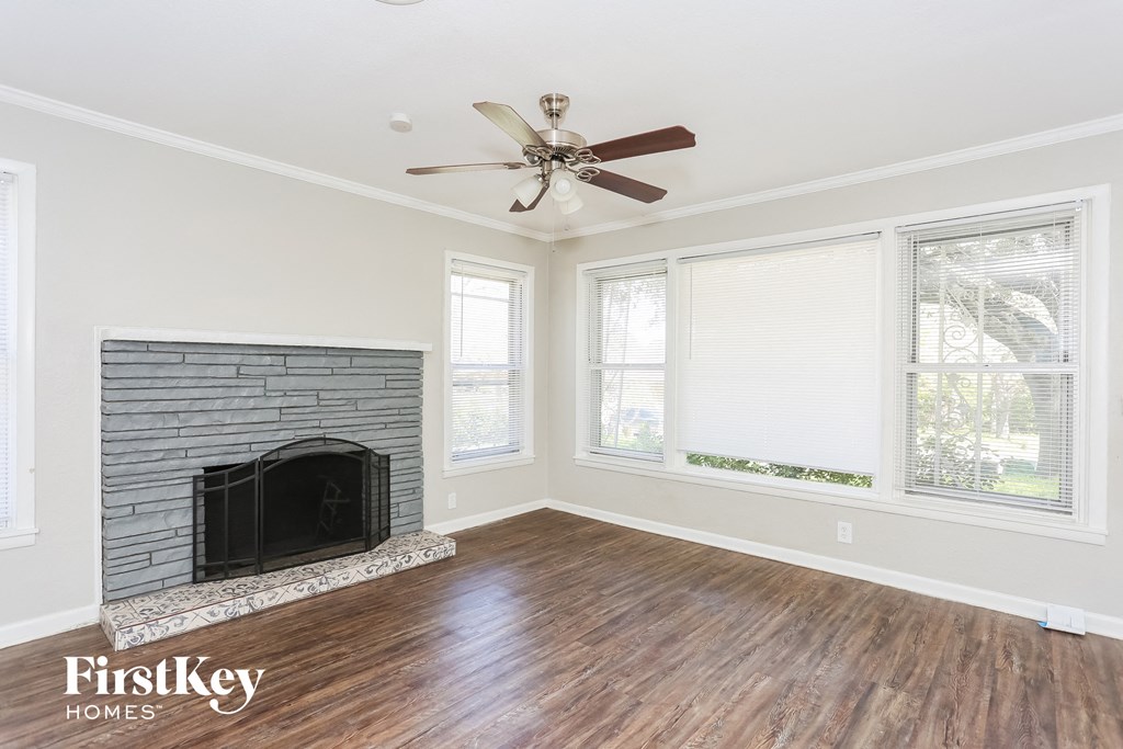 a living room with a brick fireplace and a ceiling fan
