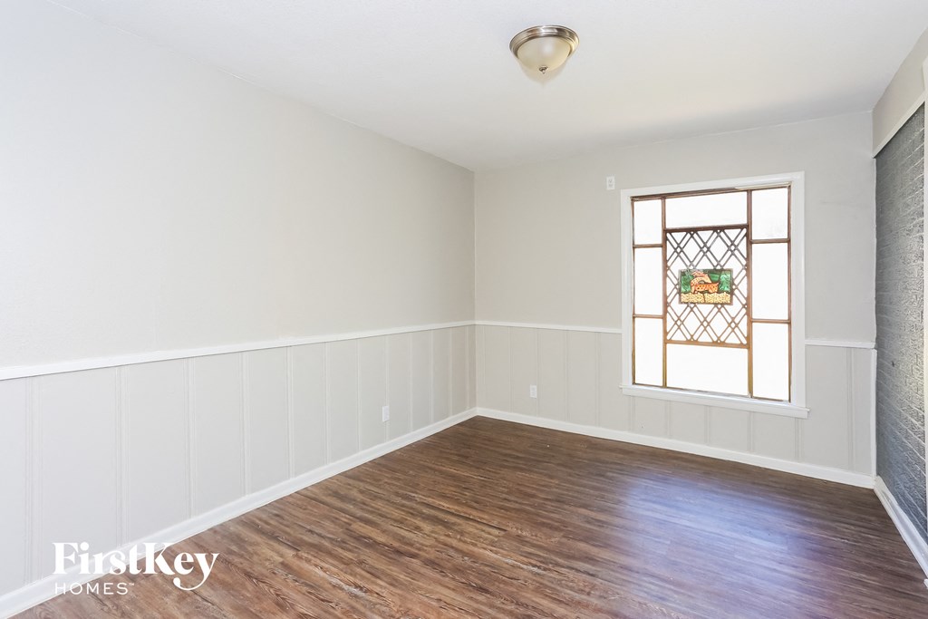 an empty living room with wood floors and a stained glass window