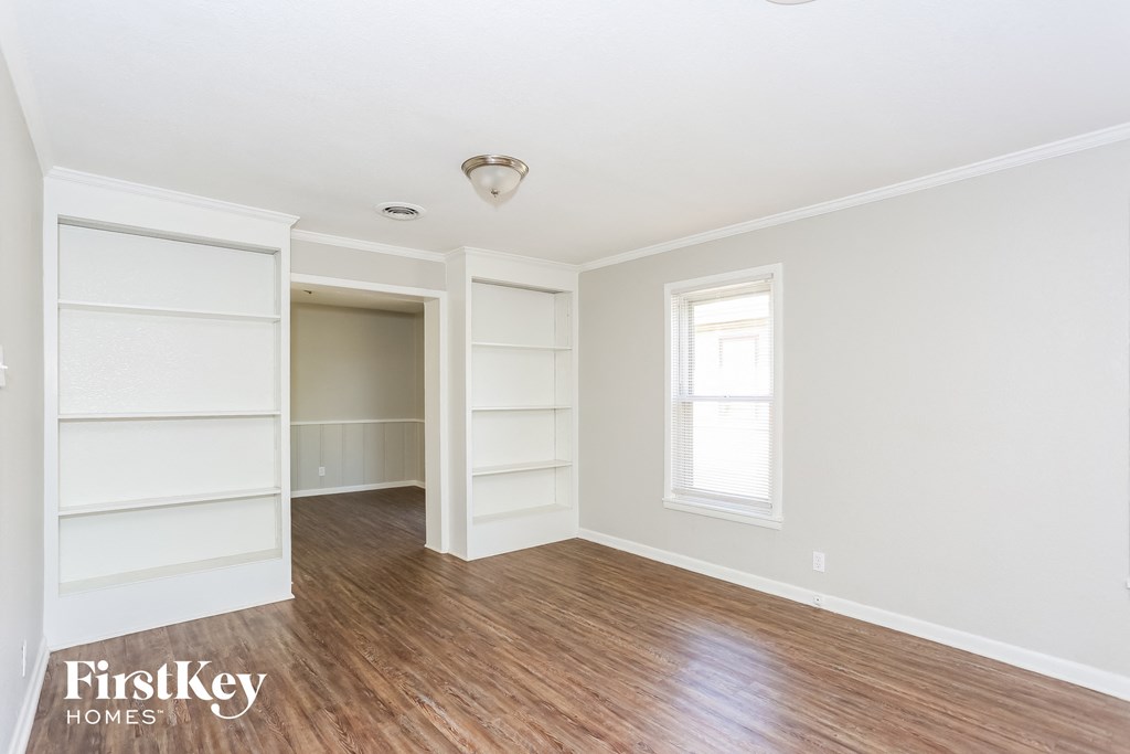 an empty room with white shelves and a window and wood floors