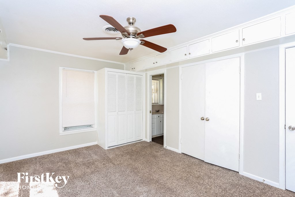 a bedroom with white closets and a ceiling fan
