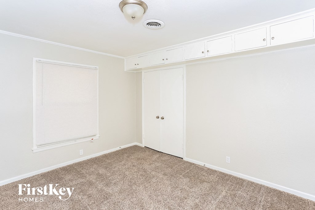 a bedroom with white walls and carpet and a window
