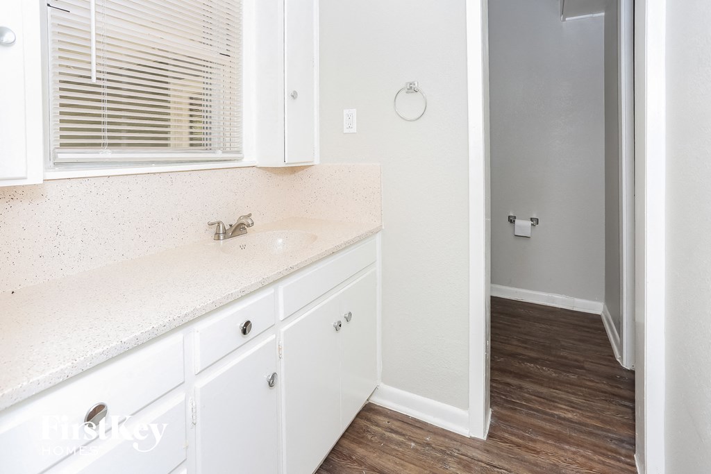 a bathroom with white cabinets and a sink and a shower