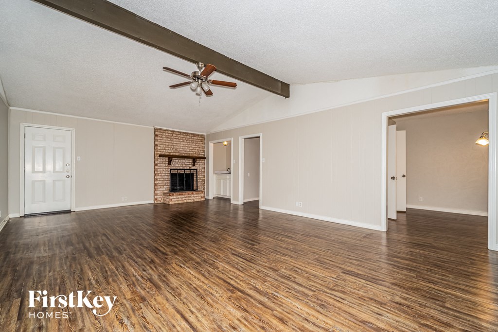 A spacious room with a fireplace and wooden floors.