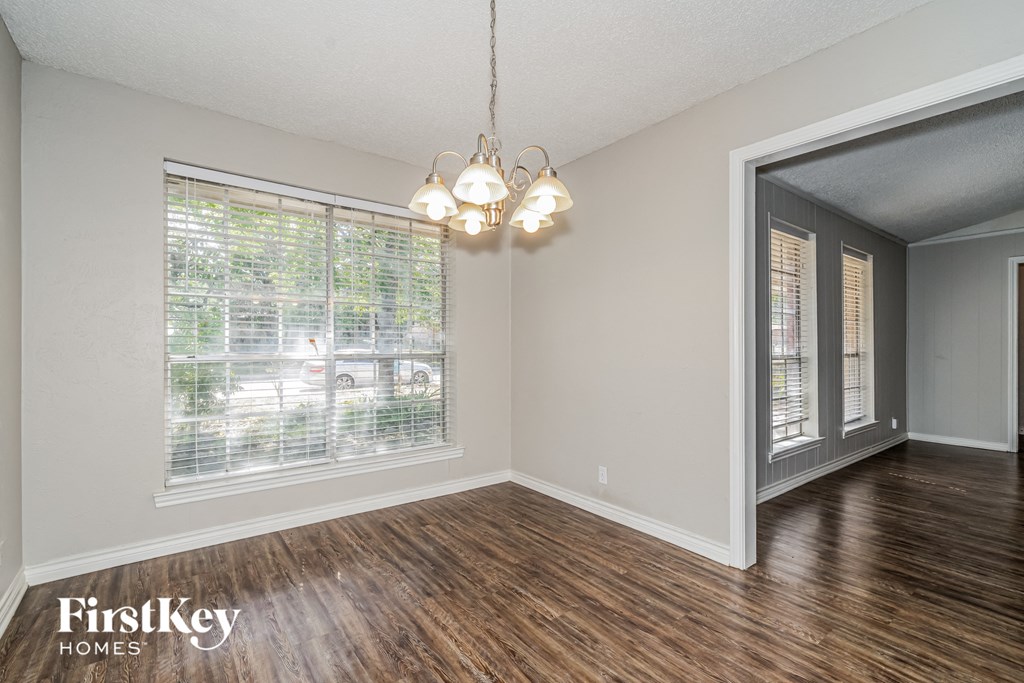 A room with wooden floors and a window with blinds.