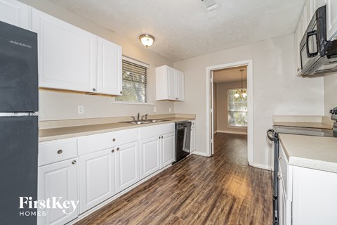 A kitchen with white cabinets and a black fridge.