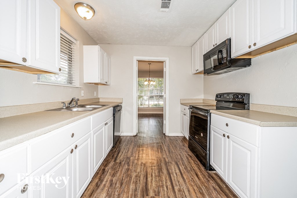 A kitchen with white cabinets and a black oven.