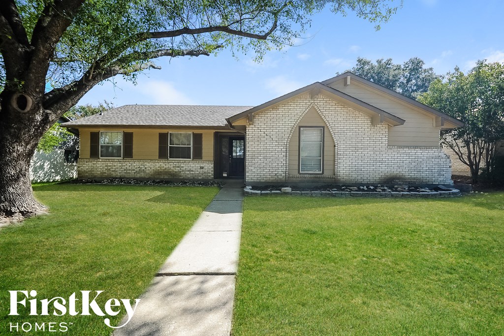 a white brick house with a lawn and a tree